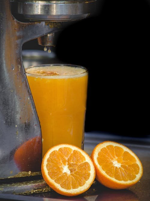 Freshly squeezed orange juice beside halved oranges — a natural source of vitamin C for collagen synthesis